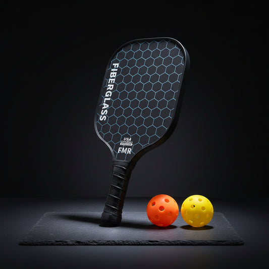 Black pickleball paddle with measurements and two balls on a white background